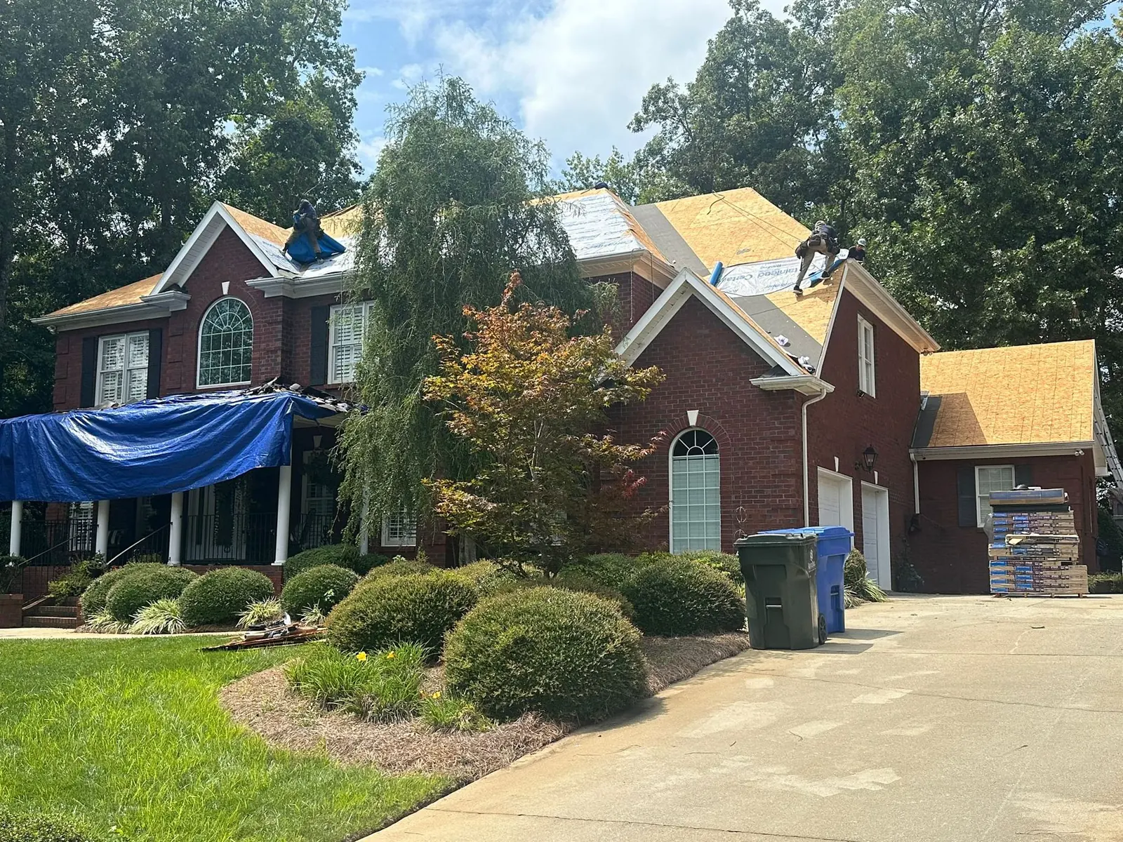 Crew replacing roof decking on a brick house