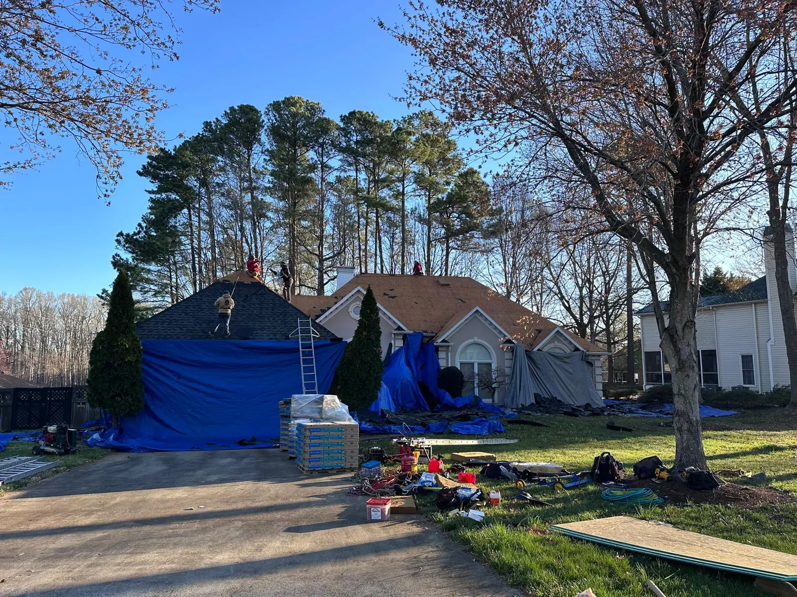 Ranch home during tear-off, with tarps protecting the yard and bushes