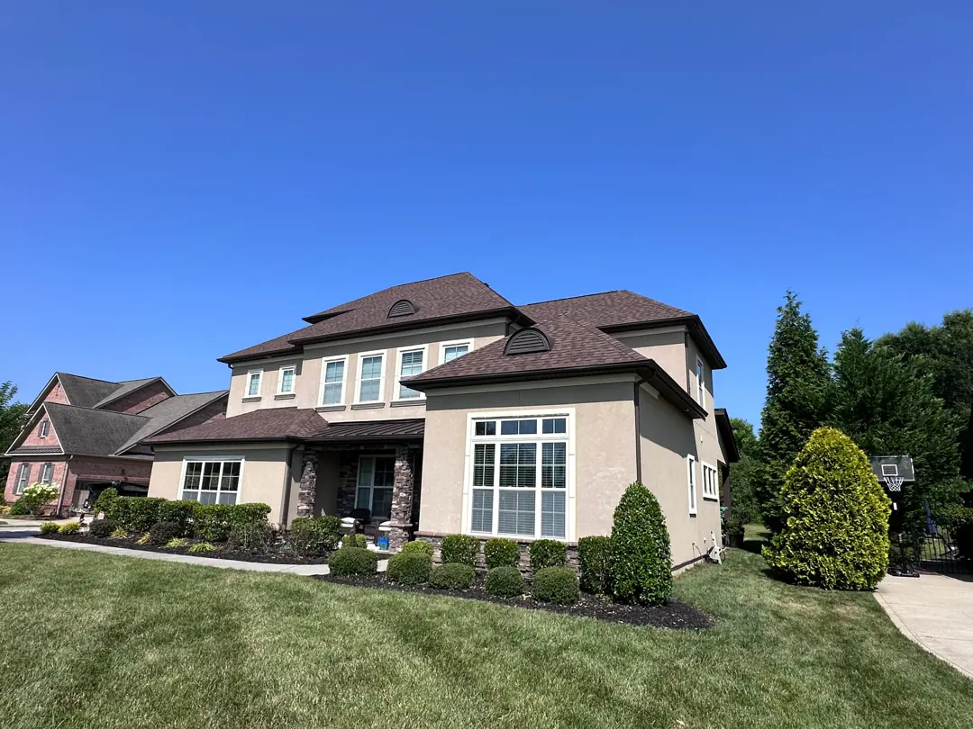 Stucco home with new brown roof from the corner
